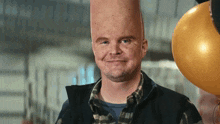 a man with a very large head is smiling while holding balloons