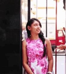 a woman in a pink floral dress is smiling