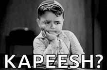 a black and white photo of a little boy sitting at a desk with his hand on his chin and the words `` kapeesh ? ''