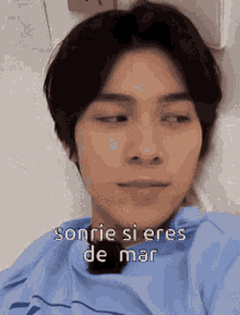 a man is laying in a hospital bed with his eyes closed and the words sonrie si eres de mar above him .