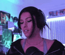 a woman wearing headphones stands in front of a microphone in a room with posters on the wall