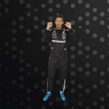 a man in a petronas racing suit is giving a thumbs up