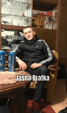 a man is sitting in a chair with a can of j on the table under him