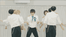 a group of men in white shirts and black pants are dancing