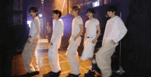 a group of young men are dancing on a stage in a dark room .