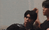 a man laying on another man 's lap with his hand on his head