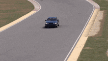 a blue car is driving down a race track with a sign that says ' toyota '