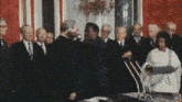 a group of people in suits are standing around a table