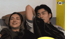 a man and a woman are laying on a bed with a yellow wall behind them that says ' cnn '