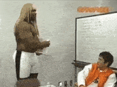 a man with long blonde hair is standing next to another man in front of a white board that says ' samurai ' on it