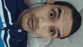 a man wearing a blue and white striped shirt and ear buds looks surprised
