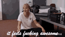 a woman sitting on the floor with the words it feels fucking awesome