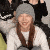 a woman wearing a gray knitted hat is smiling for the camera