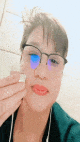 a woman wearing glasses and red lipstick holds a glass in front of her face