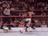 two wrestlers are fighting in a wrestling ring with a referee .