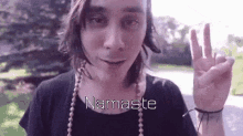 a woman is making a peace sign with her hand while wearing a necklace .
