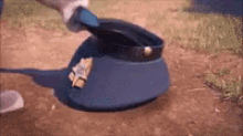 a person is cleaning a police hat with a brush on a dirt road .