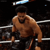 a man with a beard is standing in a wrestling ring without a shirt .