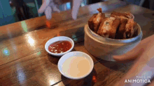 a person is dipping a piece of food in sauce on a wooden table made by animatica