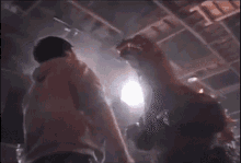 a group of people dancing in a dark room with a light shining through the ceiling