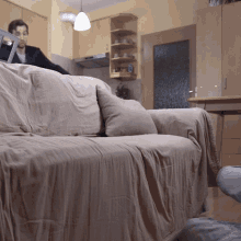 a man is sitting on a couch with a blanket on it