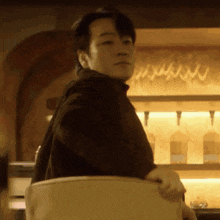 a man in a black shirt is sitting in a chair in front of a bar