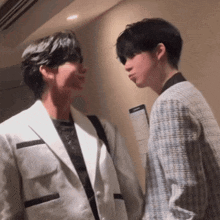 two men in suits are standing next to each other and talking to each other .