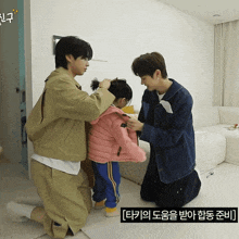 a little girl wearing a pink jacket is being helped by two men in a living room