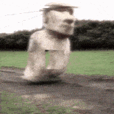a large statue of a man 's head is walking down a road