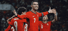 a soccer player with the number 7 on his jersey is surrounded by his teammates