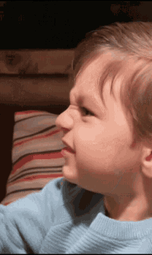 a young boy in a blue sweater looks to the side