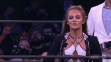 a woman is standing in a wrestling ring with a crowd behind her and a sign that says aew on it .