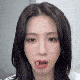 a close up of a woman 's face with a piece of meat in her mouth
