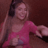 a woman wearing headphones and a pink top is dancing in a room .