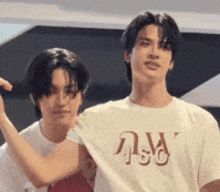 two young men are standing next to each other and one of them is wearing a t-shirt with the letter w on it