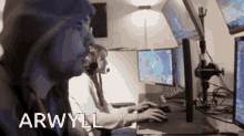 a man and a woman are sitting in front of computer monitors and the words arwytl are on the screen