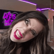 a woman with red lipstick is making a funny face and smiling .