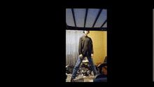 a man in a black shirt is standing in a room with a yellow wall