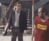 two men standing next to each other one wearing a red shirt that says runners