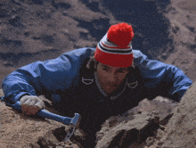 a man wearing a red and white hat with the letter d on it is climbing a rock