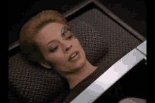 a woman is laying on a bed with a robot on her face .