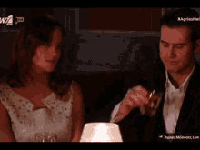 a man and a woman are sitting at a table with a candle in front of them and a sign that says agris hotel