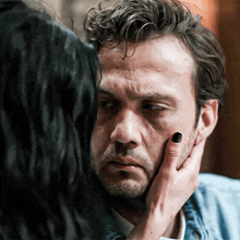a woman is touching a man 's face with her hand