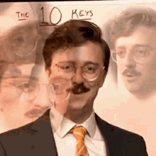 a man in a suit and tie with a mustache is standing in front of a white board with the number 10 keys .
