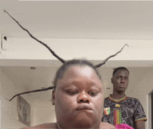 a man and a woman are standing next to each other and the woman has a very long braided hairdo