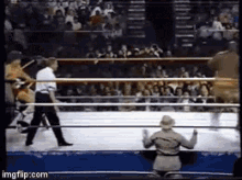 a man in a hat is kneeling down in a wrestling ring