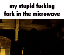 a man standing in a dark room with a fork in the microwave