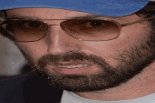 a man with a beard wearing a blue hat and sunglasses