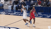 a basketball player with the number 2 on his jersey runs towards another player