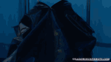 a man in a blue shirt is smiling in front of a shadowhunterstv.com advertisement